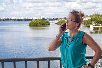 Josie Cline, MBA, Realtor, speaking to a client on her cell phone while overlooking the water