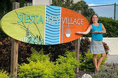 Josie Cline MBA Realtor standing near Siesta Key Village sign for property video