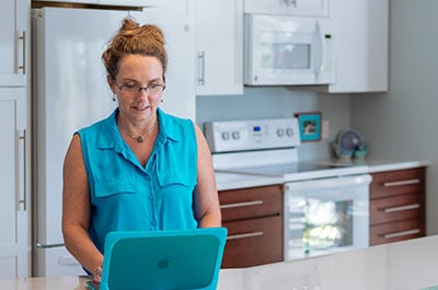 Josie Cline MBA Realtor researching on a laptop in a kitchen