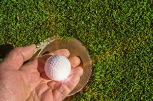 Man picking up golf ball out of the cup