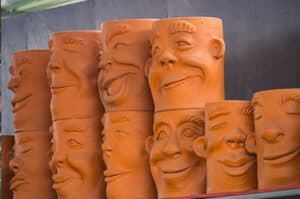 Shelf displaying terracotta pots with funny faces