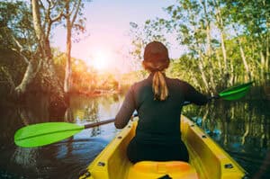 View of woman kayaking through mangroves