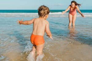 Young boy running into the gulf towards his mom at the beach