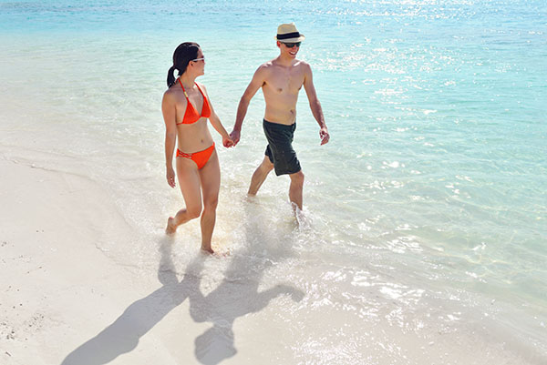 Young couple walking along the white sand beach